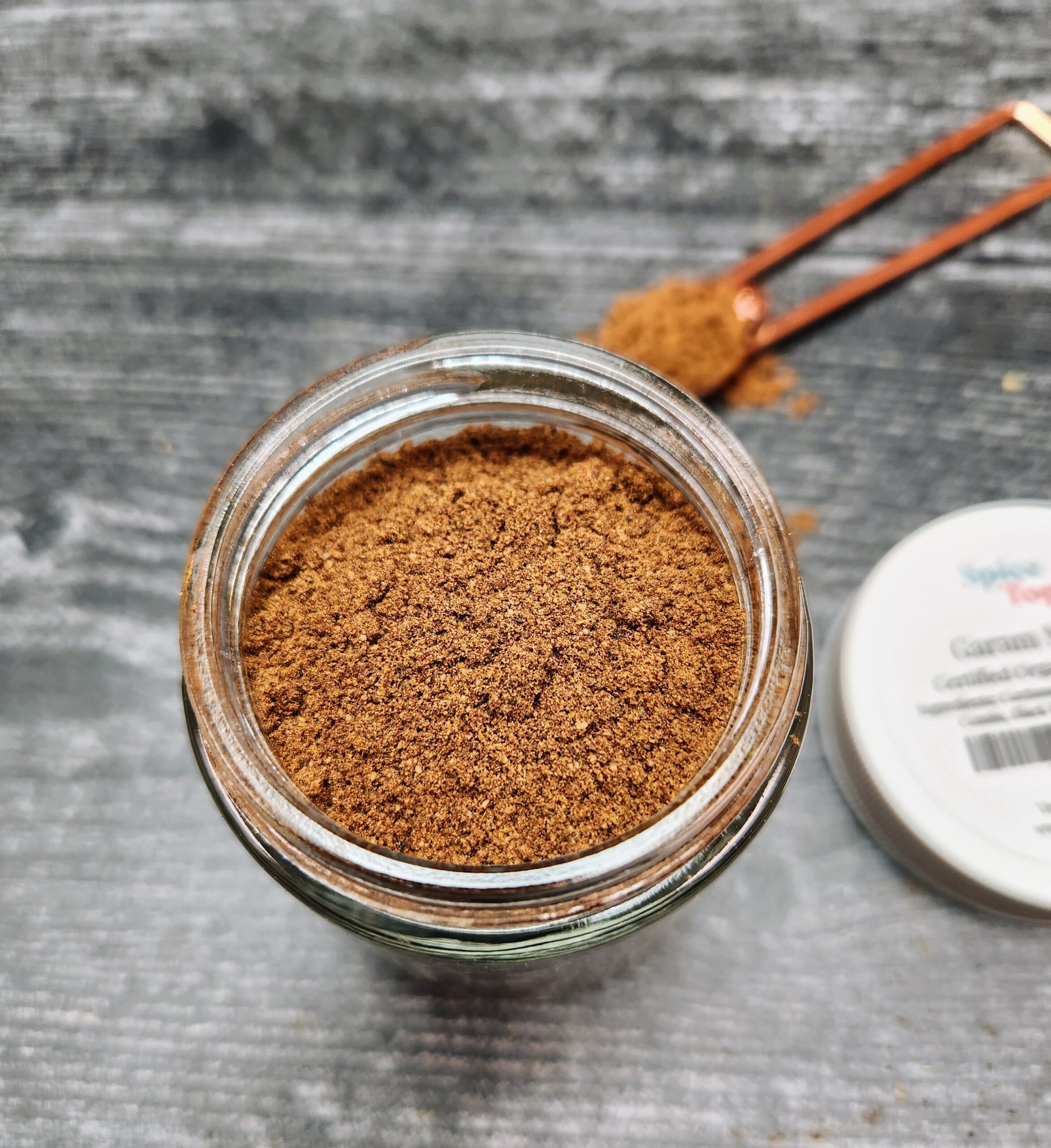 A close up image of an open jar of Garam Masala spice blend.